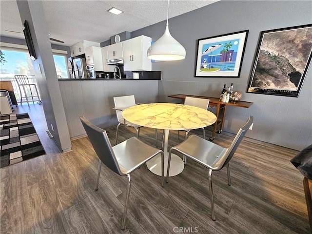 dining area with dark wood-type flooring and a textured ceiling