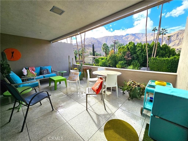 view of patio featuring outdoor lounge area, a mountain view, and a balcony