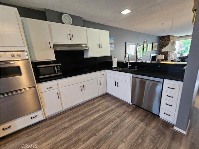 kitchen with appliances with stainless steel finishes, dark hardwood / wood-style flooring, a textured ceiling, sink, and white cabinets