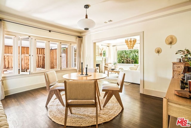 dining area with plenty of natural light, dark hardwood / wood-style floors, ornamental molding, and an inviting chandelier