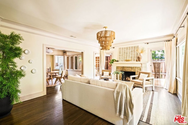 living room featuring a chandelier, dark wood-type flooring, a tile fireplace, and a healthy amount of sunlight