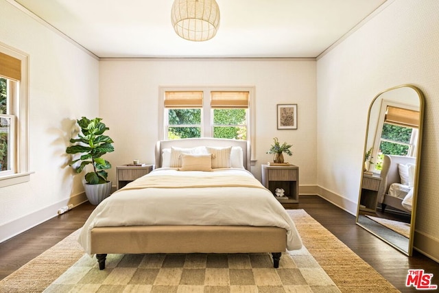 bedroom featuring dark hardwood / wood-style floors, crown molding, and multiple windows