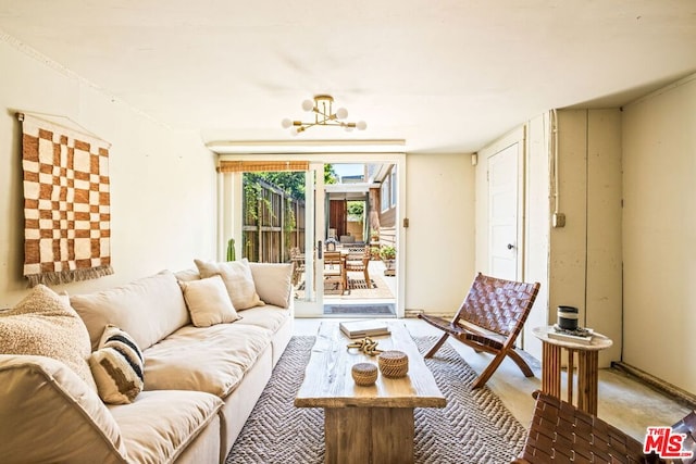 living room featuring concrete flooring and a notable chandelier