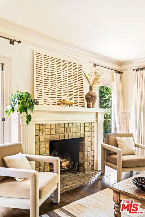 living area with dark hardwood / wood-style flooring, ornamental molding, and a tile fireplace