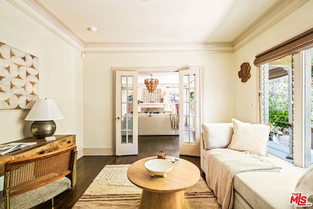 living area with a notable chandelier, dark hardwood / wood-style floors, crown molding, and french doors