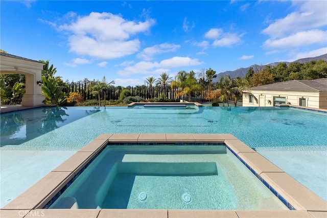 view of swimming pool featuring an in ground hot tub and a mountain view