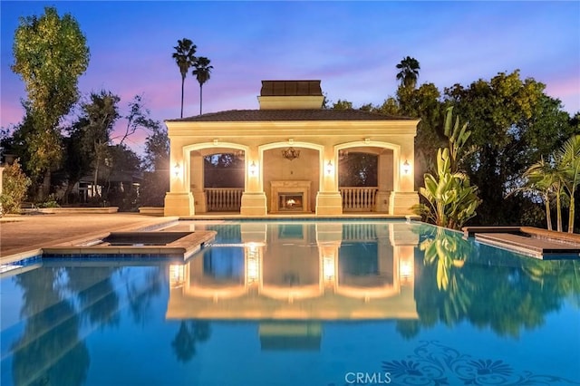 pool at dusk with an in ground hot tub