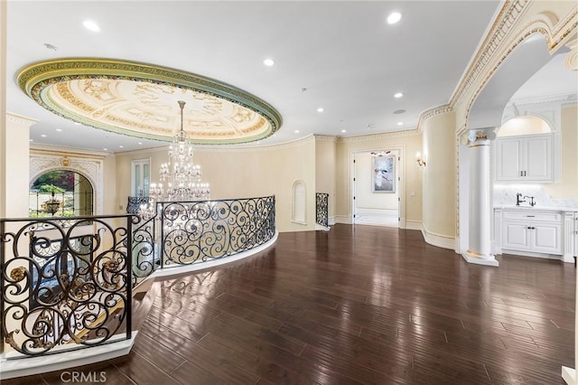 hallway with a tray ceiling, ornate columns, dark hardwood / wood-style flooring, and sink