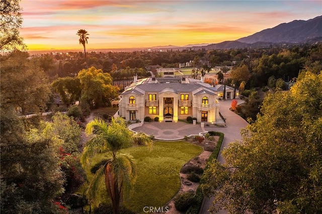 back house at dusk featuring a mountain view and a yard