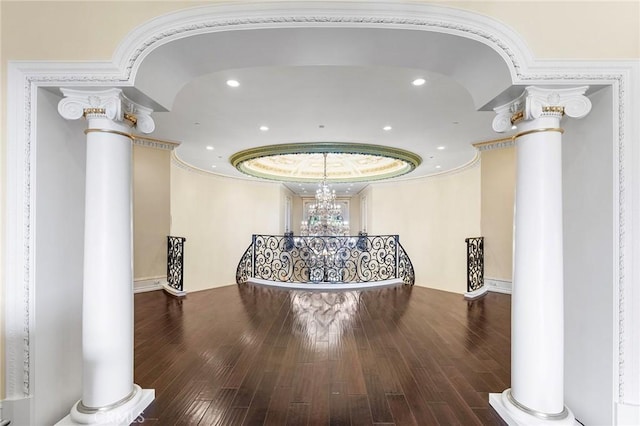 corridor featuring an inviting chandelier, wood-type flooring, and ornate columns