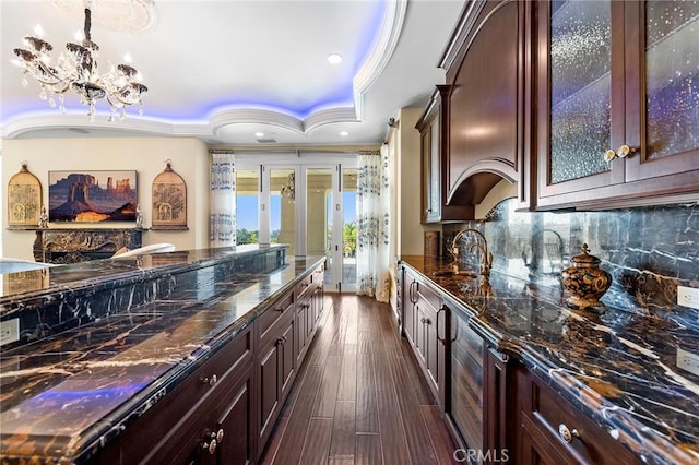 kitchen with dark hardwood / wood-style floors, a raised ceiling, dark brown cabinets, and sink