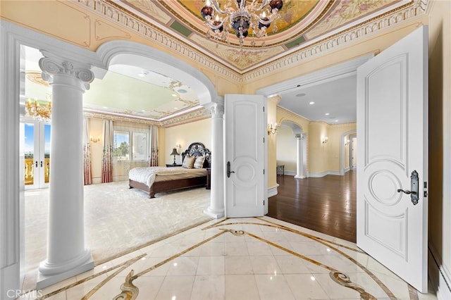 bedroom with hardwood / wood-style flooring, a notable chandelier, ornate columns, and crown molding