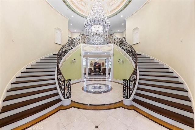 staircase featuring tile patterned flooring, a high ceiling, a chandelier, and crown molding