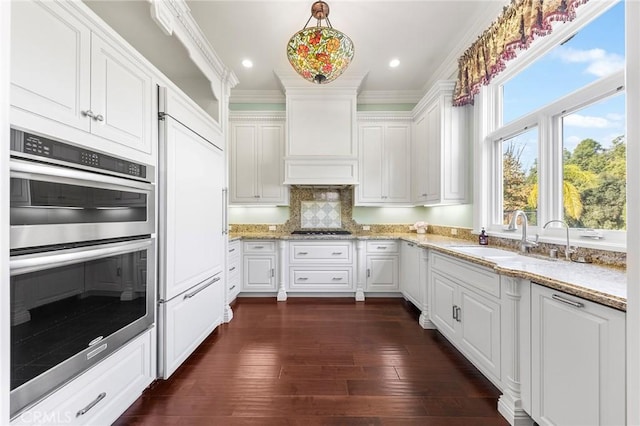 kitchen featuring double oven, dark wood-type flooring, sink, crown molding, and white cabinetry