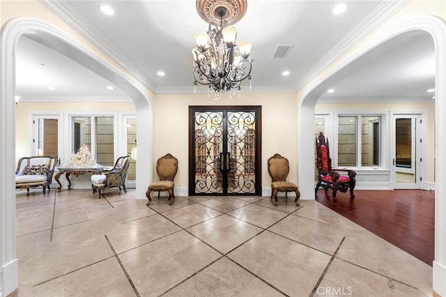 foyer featuring light wood-type flooring, crown molding, and french doors