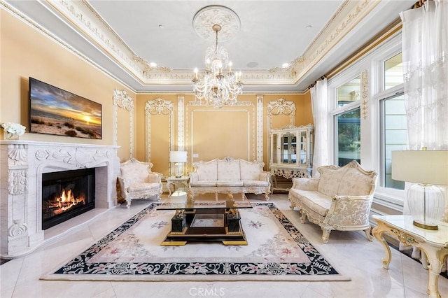 living area featuring an inviting chandelier, a raised ceiling, crown molding, and a premium fireplace