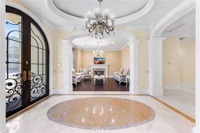 tiled foyer featuring a tray ceiling, ornate columns, french doors, and ornamental molding