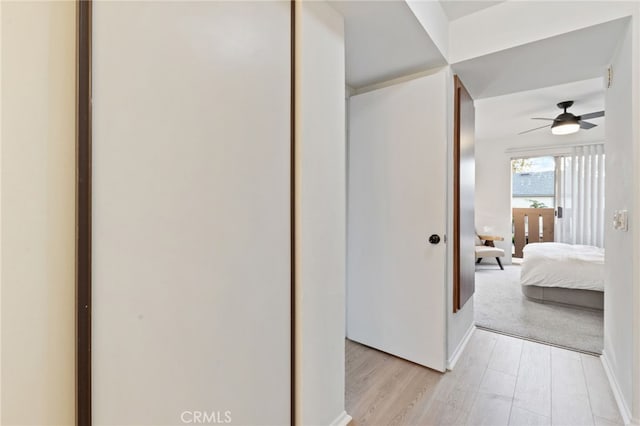 corridor with baseboards and light wood-style flooring