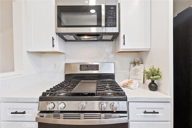 kitchen with white cabinets, stainless steel appliances, and light stone countertops