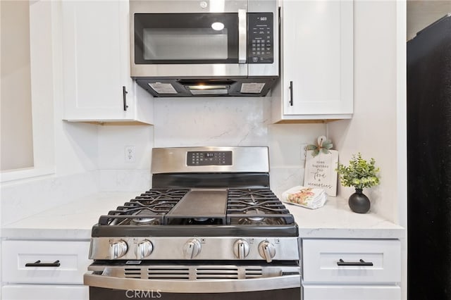 81 Smokestone Unit 12, Irvine, CA 92614 - kitchen featuring appliances with stainless steel finishes, white cabinets, decorative backsplash, and light stone counters