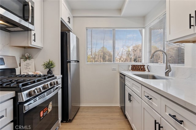 kitchen featuring a sink, light countertops, baseboards, light wood-style floors, and stainless steel appliances