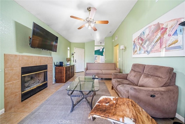 living room featuring a tile fireplace, ceiling fan, and light tile patterned floors