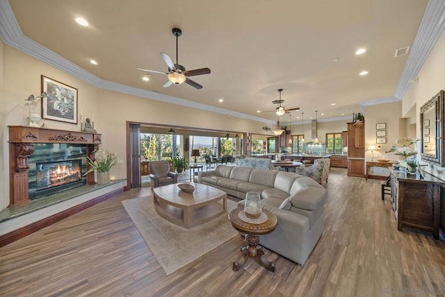 living room with a fireplace, hardwood / wood-style flooring, ceiling fan, and crown molding