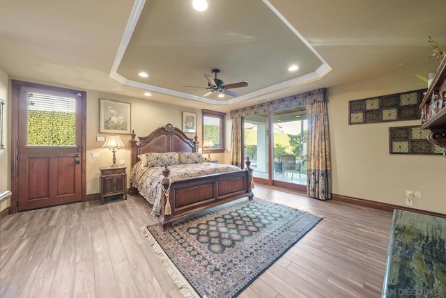 bedroom with ceiling fan, light hardwood / wood-style flooring, access to outside, and a tray ceiling