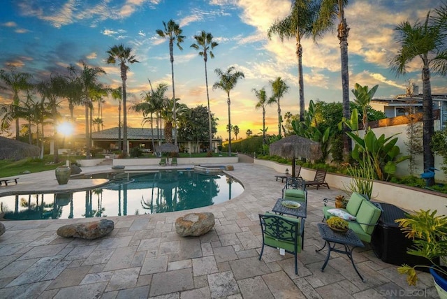 pool at dusk featuring a patio area