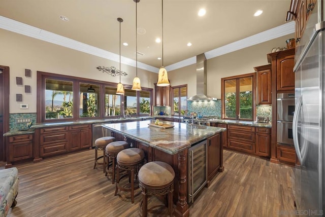 kitchen with pendant lighting, wall chimney range hood, wine cooler, plenty of natural light, and a kitchen island