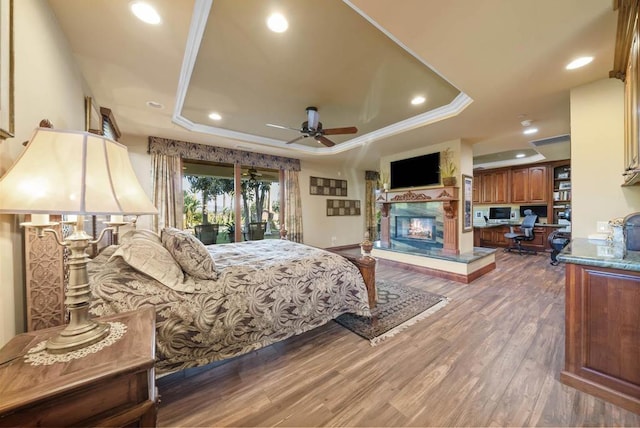 bedroom featuring wood-type flooring, access to outside, a raised ceiling, and crown molding