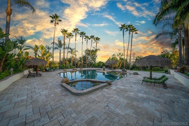 pool at dusk with a gazebo, a patio area, and an in ground hot tub