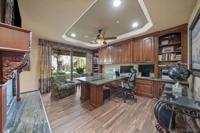 office space with hardwood / wood-style floors, built in desk, ornamental molding, and a tray ceiling