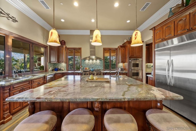 kitchen with light stone countertops, appliances with stainless steel finishes, tasteful backsplash, a spacious island, and pendant lighting