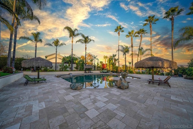 pool at dusk with a gazebo and a patio area