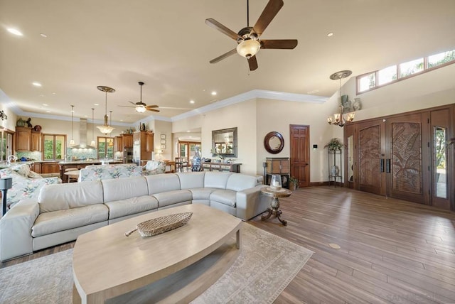 living room with ceiling fan with notable chandelier, light wood-type flooring, ornamental molding, and french doors