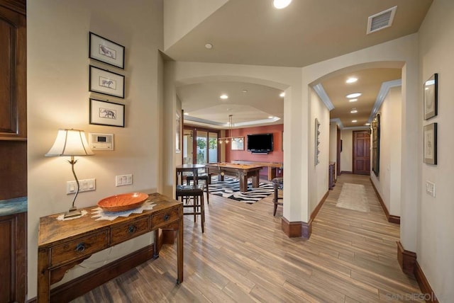 hallway with light wood-type flooring and crown molding