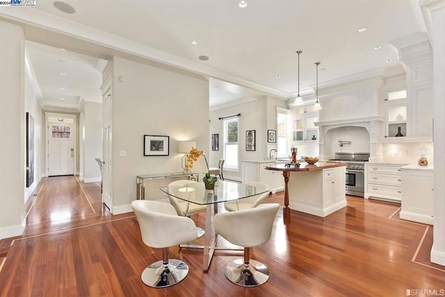 dining area with crown molding, sink, and hardwood / wood-style flooring