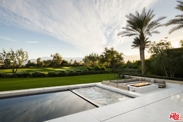 pool at dusk featuring a lawn, a patio area, and an outdoor fire pit