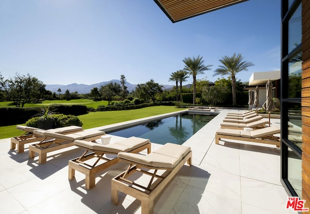 view of swimming pool with a mountain view, a patio area, and a yard