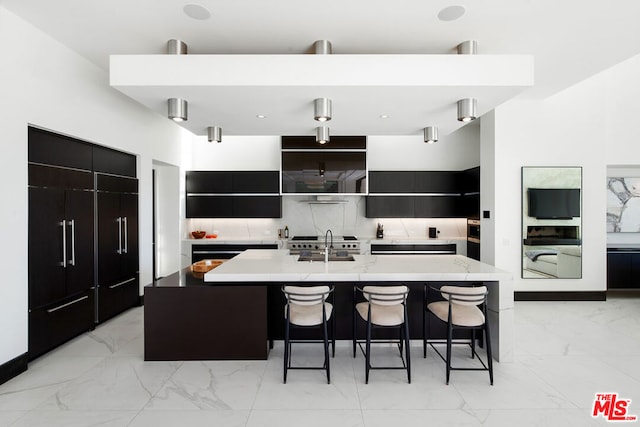 kitchen featuring sink, decorative backsplash, an island with sink, a breakfast bar area, and washer / clothes dryer