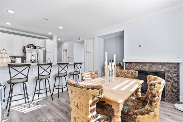 13559 Mashona Ave, Chino, CA 91710 - dining room featuring crown molding, light wood finished floors, recessed lighting, and a glass covered fireplace