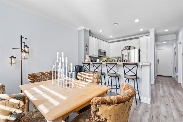 dining space with crown molding and light hardwood / wood-style flooring