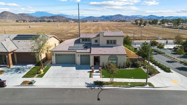 view of front of property with solar panels, a garage, and a mountain view