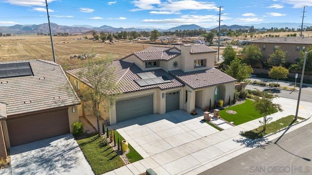 view of front of house featuring a mountain view, solar panels, and a garage