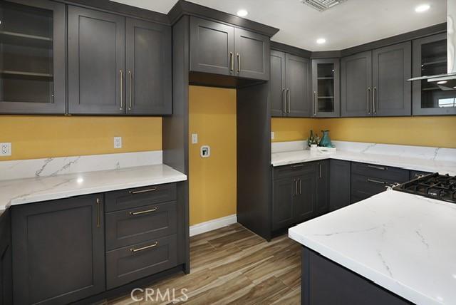 8121 San Mateo Cir, Buena Park, CA 90620 - kitchen featuring light stone countertops, wood-type flooring, and exhaust hood