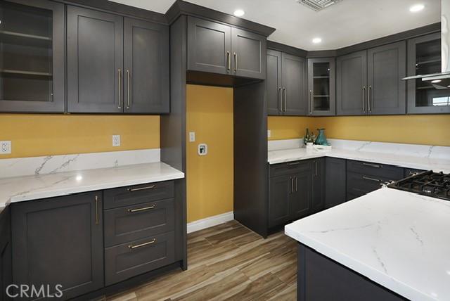 8121 San Mateo Cir, Buena Park, CA 90620 - kitchen featuring baseboards, wood finished floors, light stone countertops, glass insert cabinets, and recessed lighting