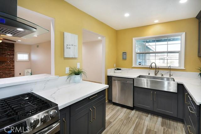8121 San Mateo Cir, Buena Park, CA 90620 - kitchen featuring sink, light stone counters, ventilation hood, appliances with stainless steel finishes, and light wood-type flooring