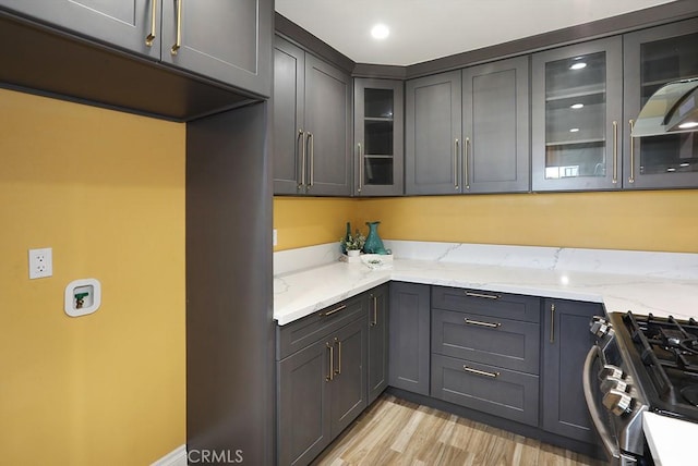 8121 San Mateo Cir, Buena Park, CA 90620 - kitchen featuring stainless steel gas stove, light stone counters, glass insert cabinets, light wood-type flooring, and gray cabinetry
