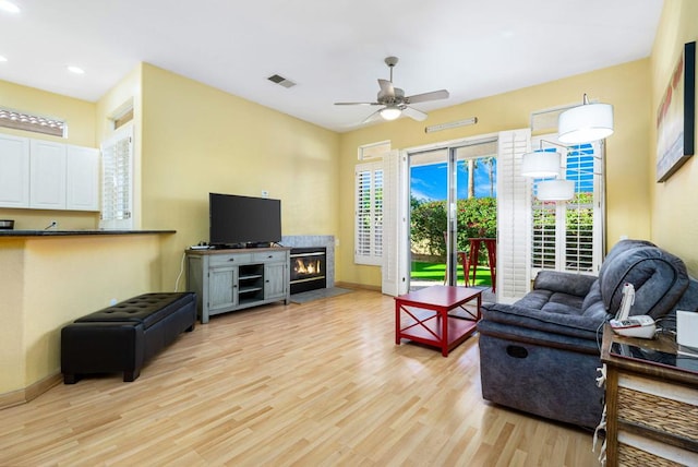 living room with light wood-type flooring, ceiling fan, and a healthy amount of sunlight